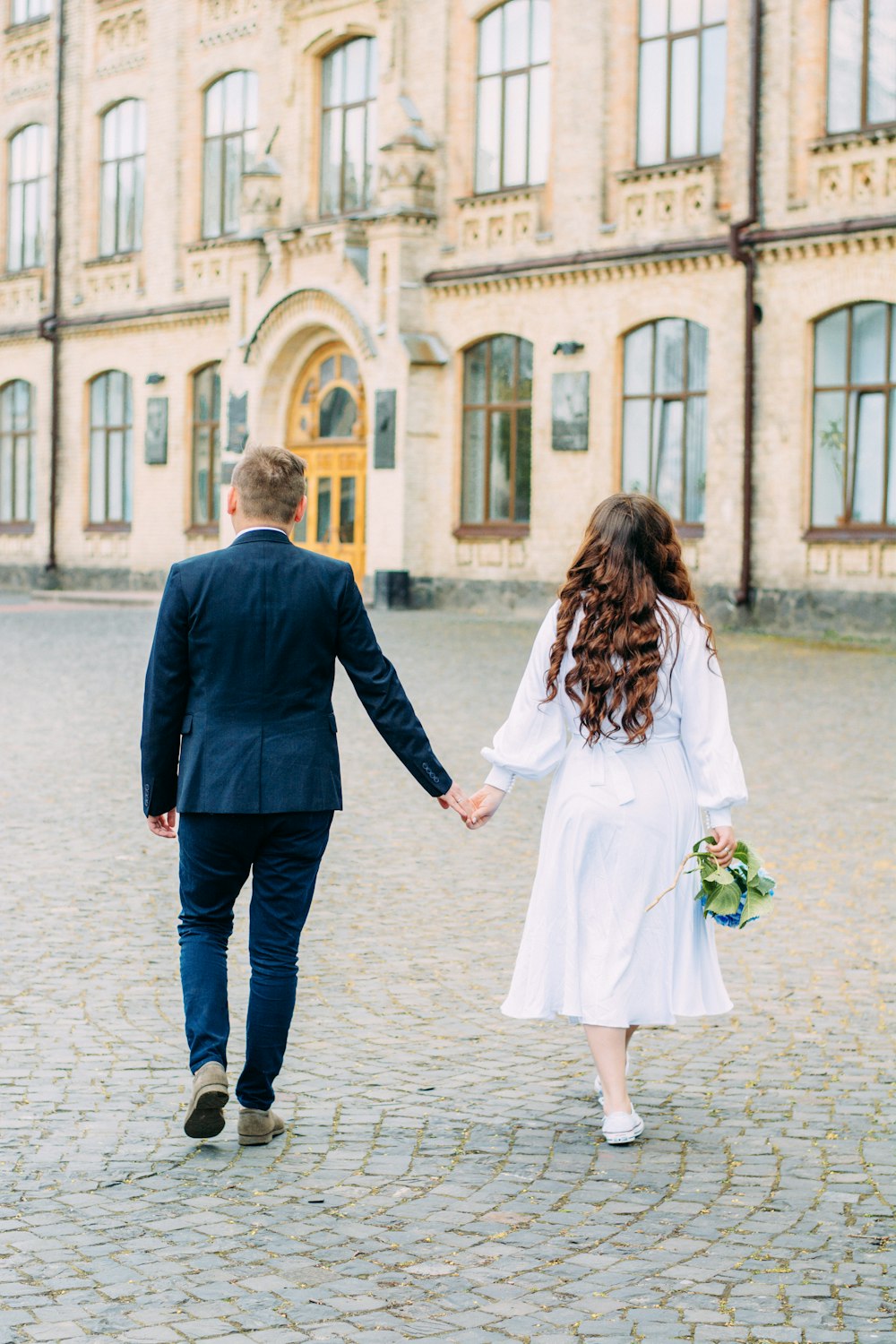 man in black suit jacket holding woman in white dress