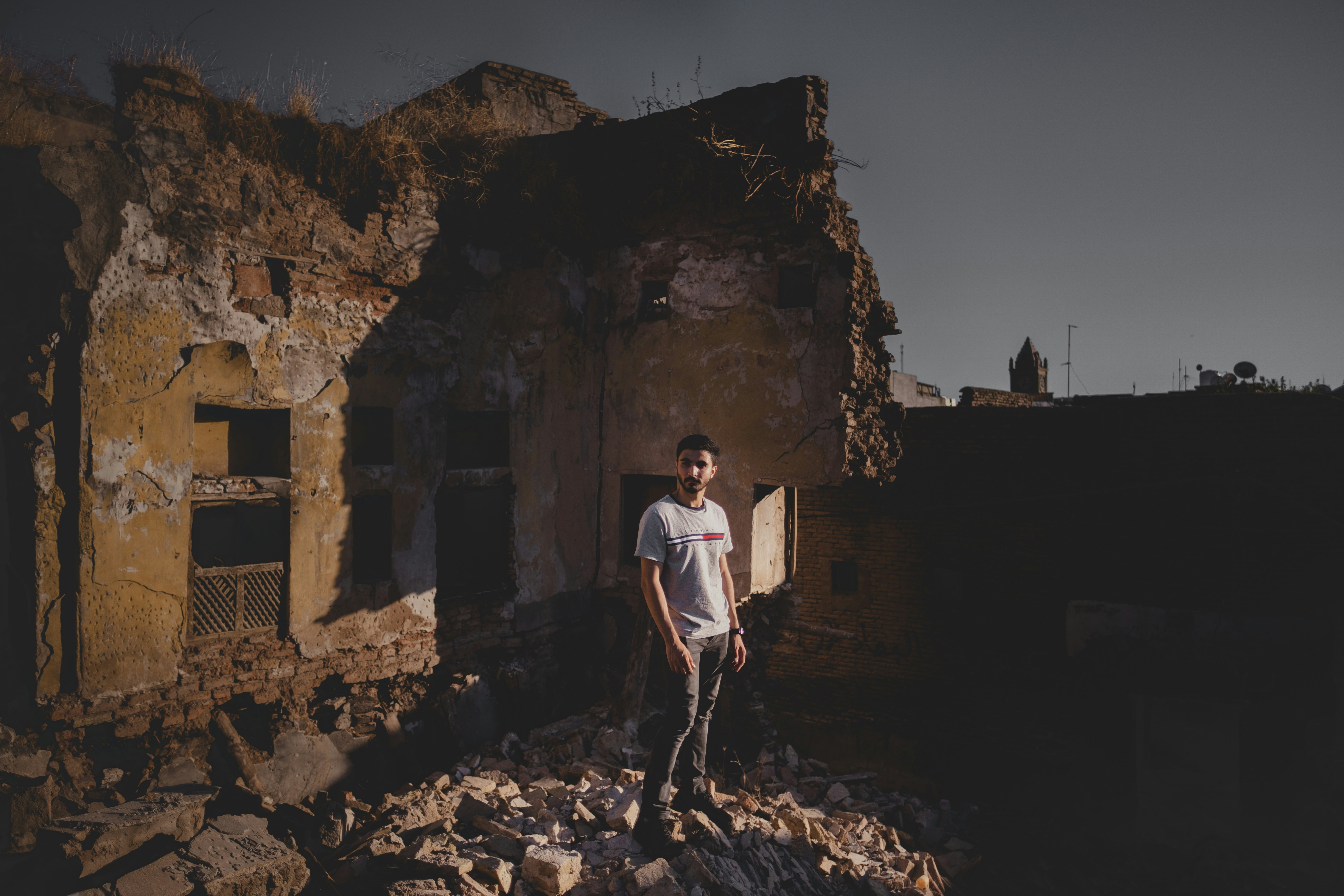 man in white t-shirt and black pants standing on brown rock formation during daytime