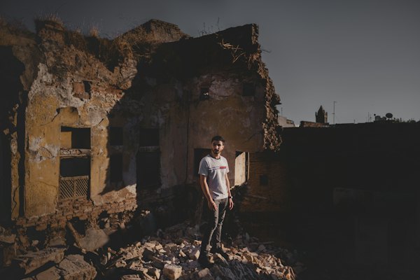 Man in white t-shirt and black pants standing on brown rock formation during daytime — Erbil, Iraq