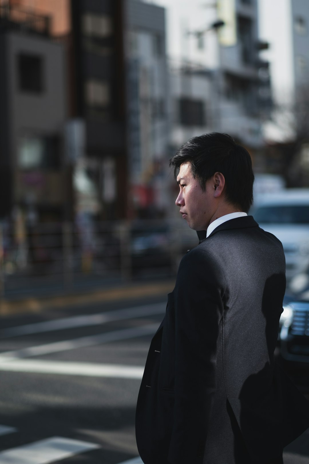 man in black suit jacket standing on sidewalk during daytime