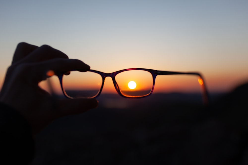 person holding brown framed eyeglasses