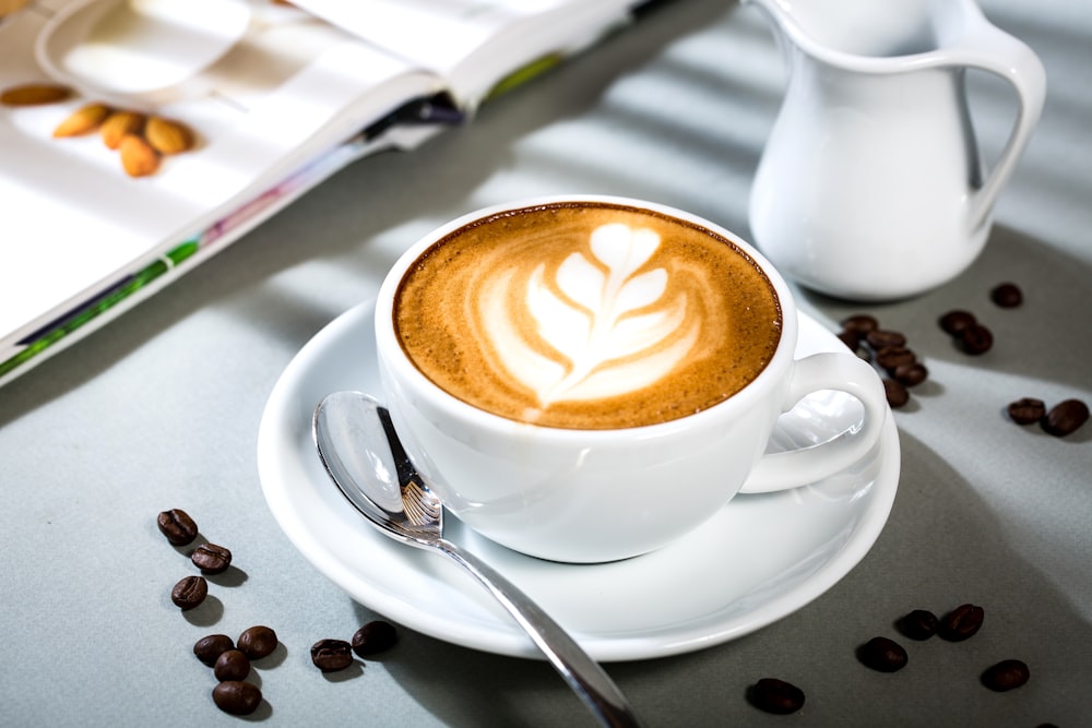 weiße Keramiktasse mit Untertasse und Edelstahllöffel