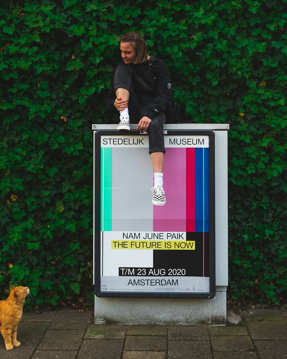 Femme en veste en cuir noir debout à côté d’un mur vert et rouge