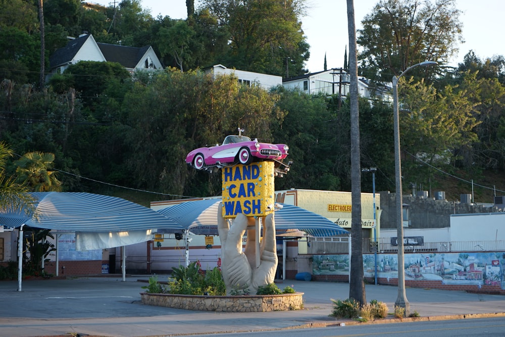 a pink car on top of a sign in a parking lot