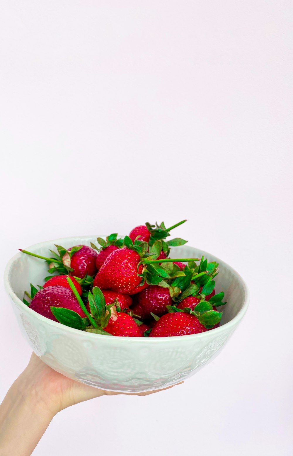red strawberries in white ceramic bowl