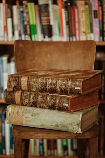 brown hardbound books on brown wooden shelf
