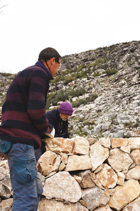 Groupe de participants construisant un mur en pierre pour un bâtiment communautaire.