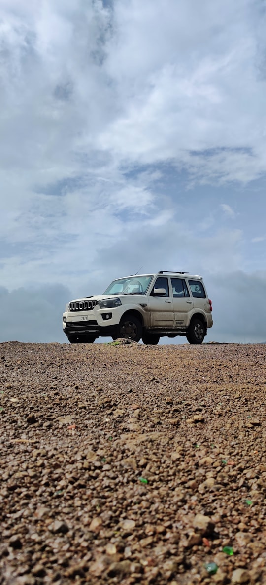 white suv on brown soil under white clouds during daytime in Panchgani India