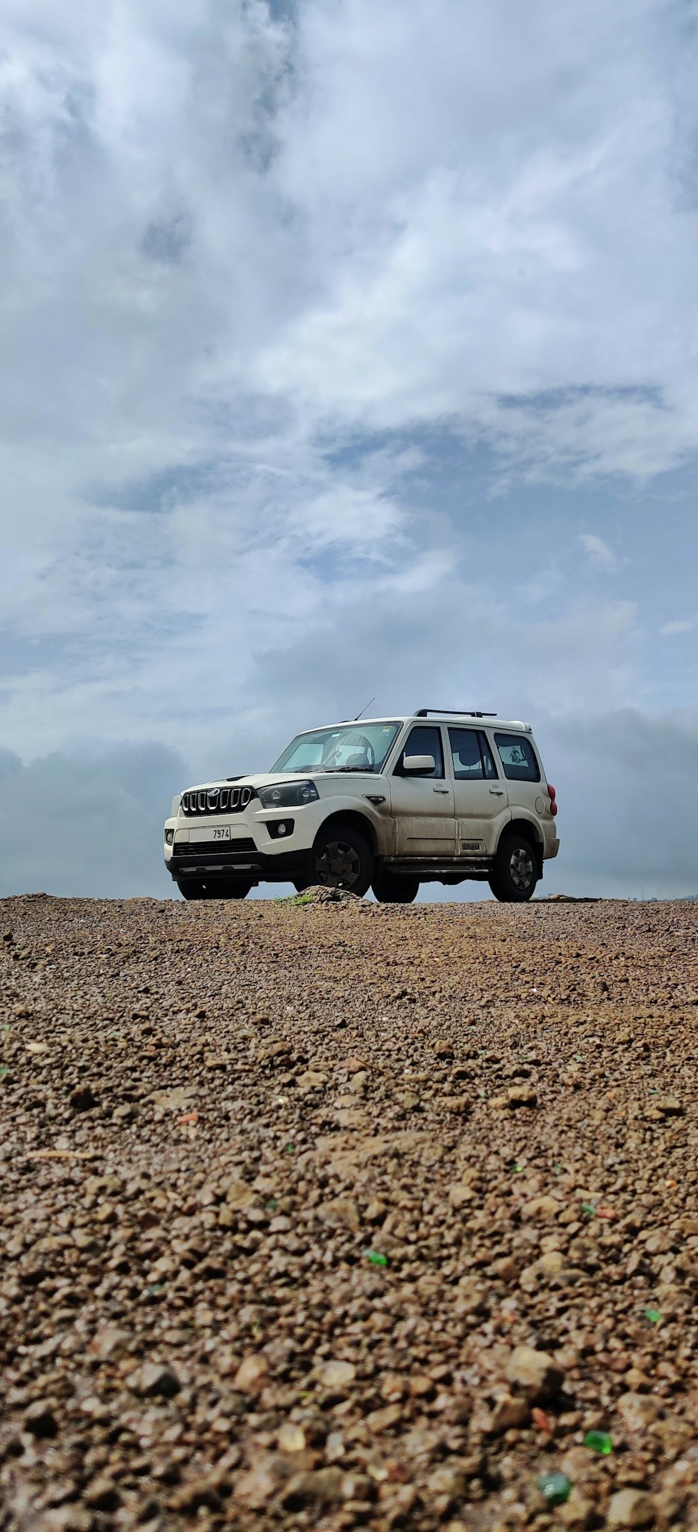 white suv on brown soil under white clouds during daytime