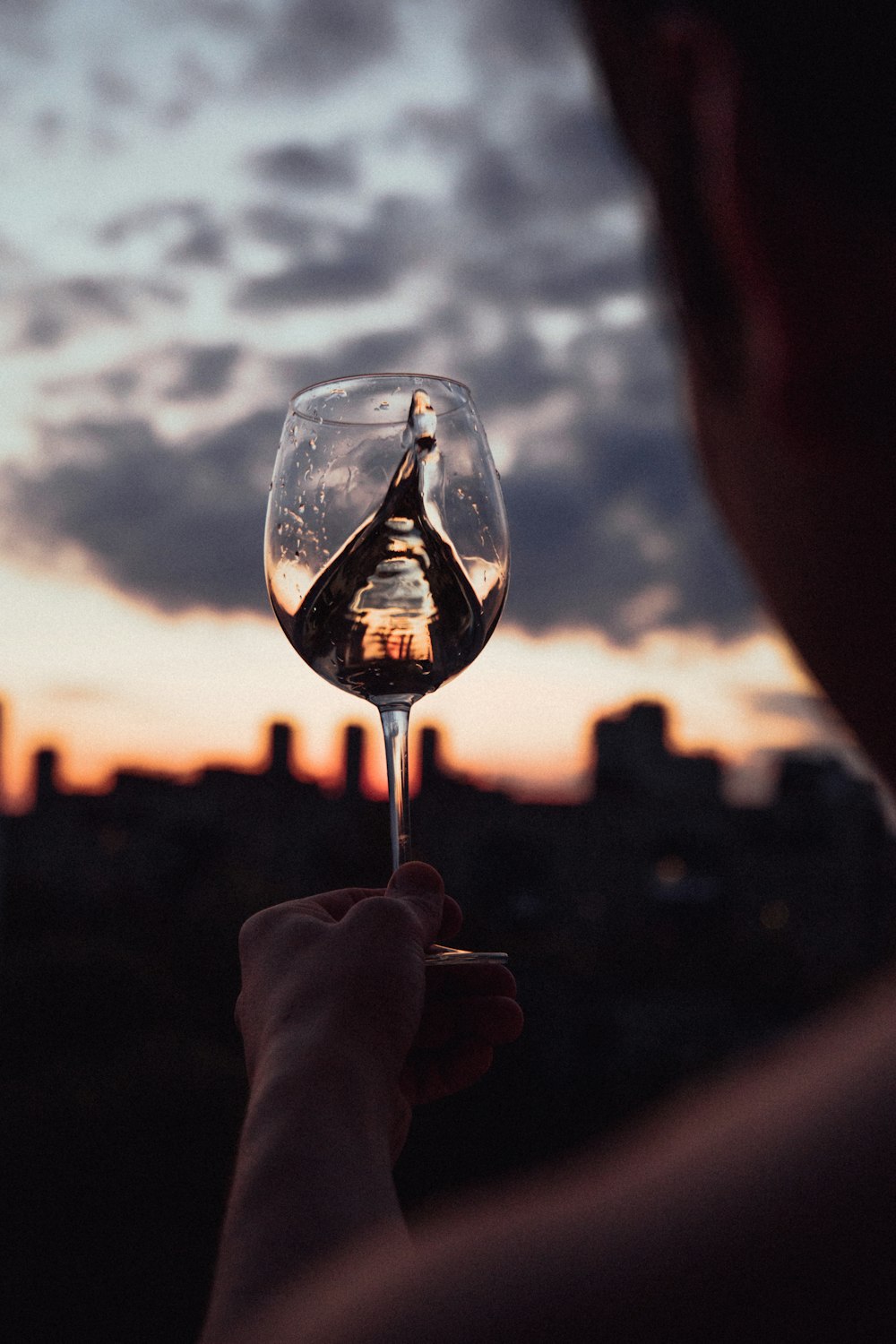 person holding clear wine glass during sunset