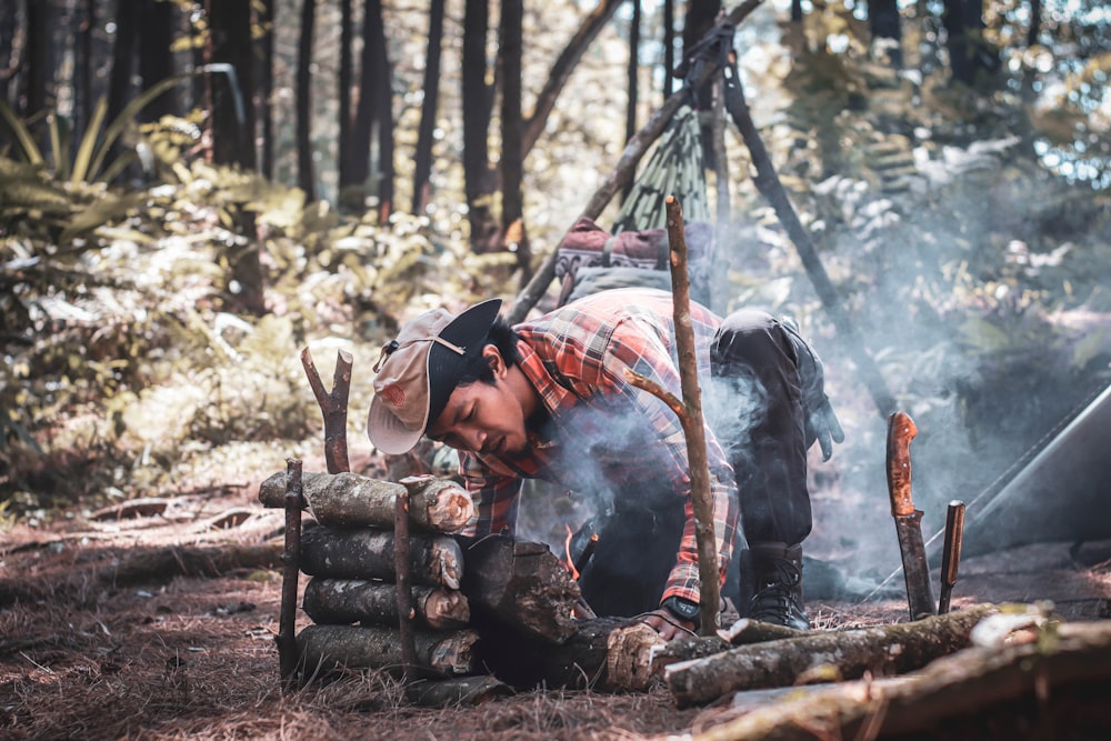 man in blue denim jacket and black knit cap sitting on brown wooden log during daytime