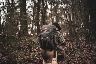 man in black and white checkered dress shirt and brown pants carrying black backpack