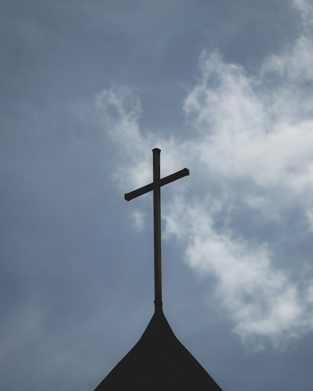 brown wooden cross under white clouds and blue sky during daytime