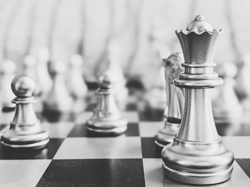 Close-up of a trophy awarded to a tournament winner with chess pieces in the background.