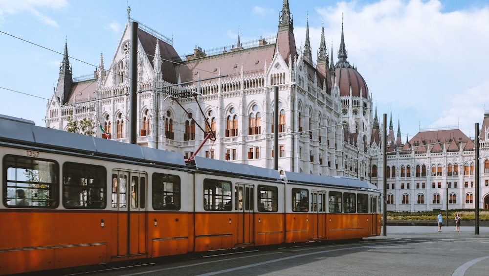 orange and white tram near white concrete building during daytime