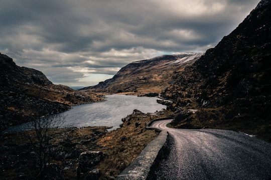 brown and gray mountain beside body of water under cloudy sky during daytime in Gap of Dunloe Ireland