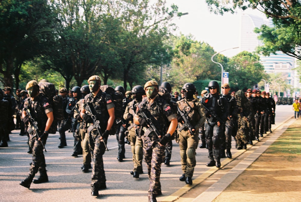 group of men in black and brown camouflage uniform standing on gray asphalt road during daytime