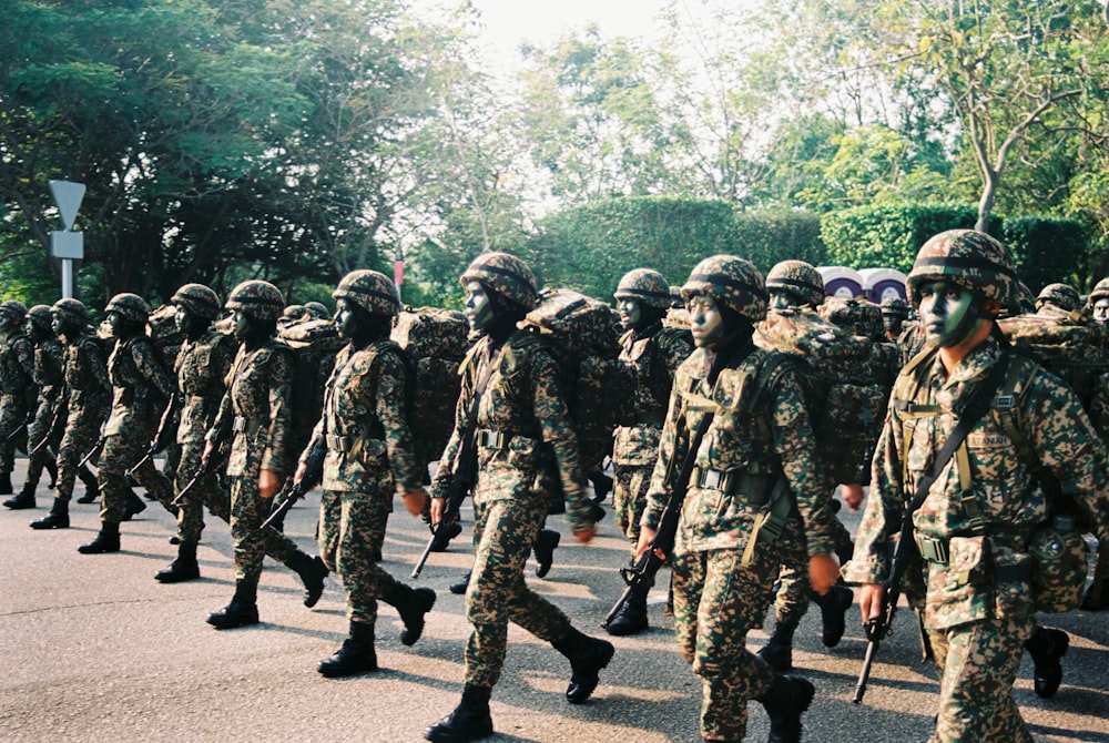 group of men in camouflage uniform standing on road during daytime