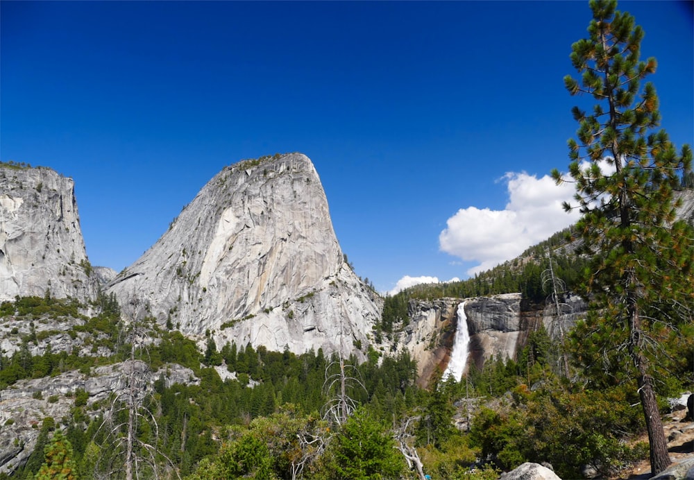 green grass and gray rocky mountain under blue sky during daytime