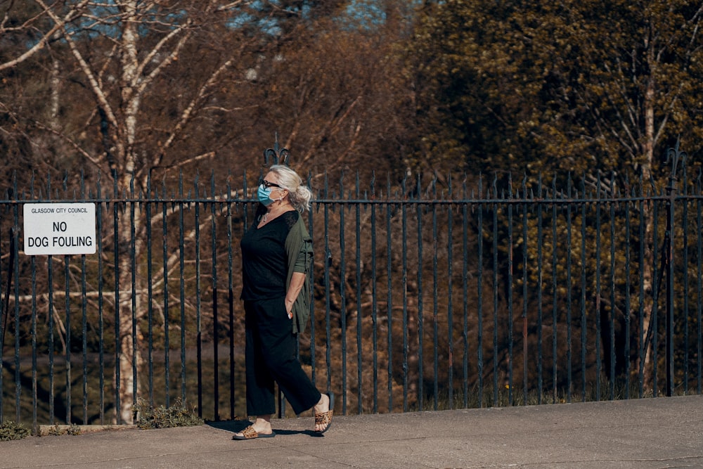 man in black jacket and black pants walking on sidewalk during daytime