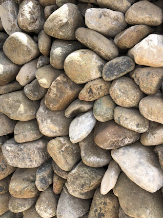 A pile of smooth, decorative stones in various natural colors ready for delivery