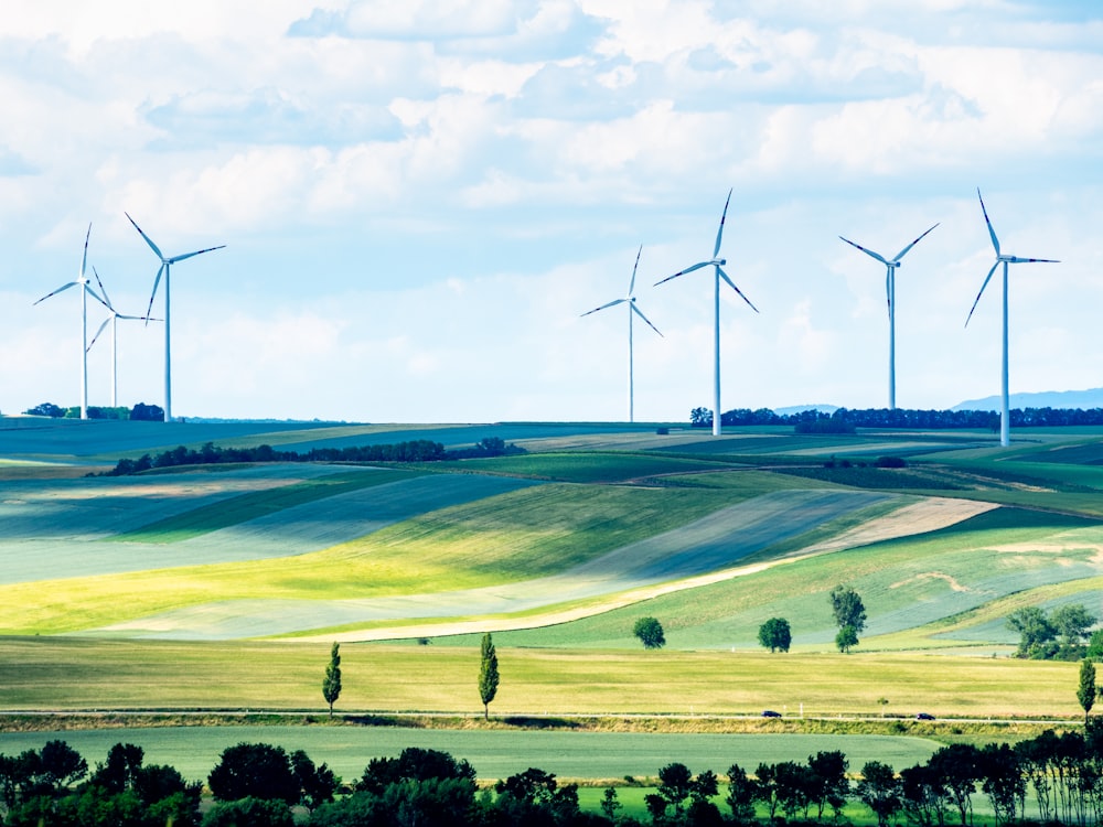 wind turbines on green grass field under white clouds during daytime