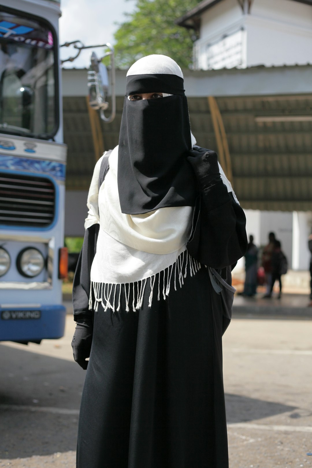woman in white hijab and black abaya standing on street during daytime