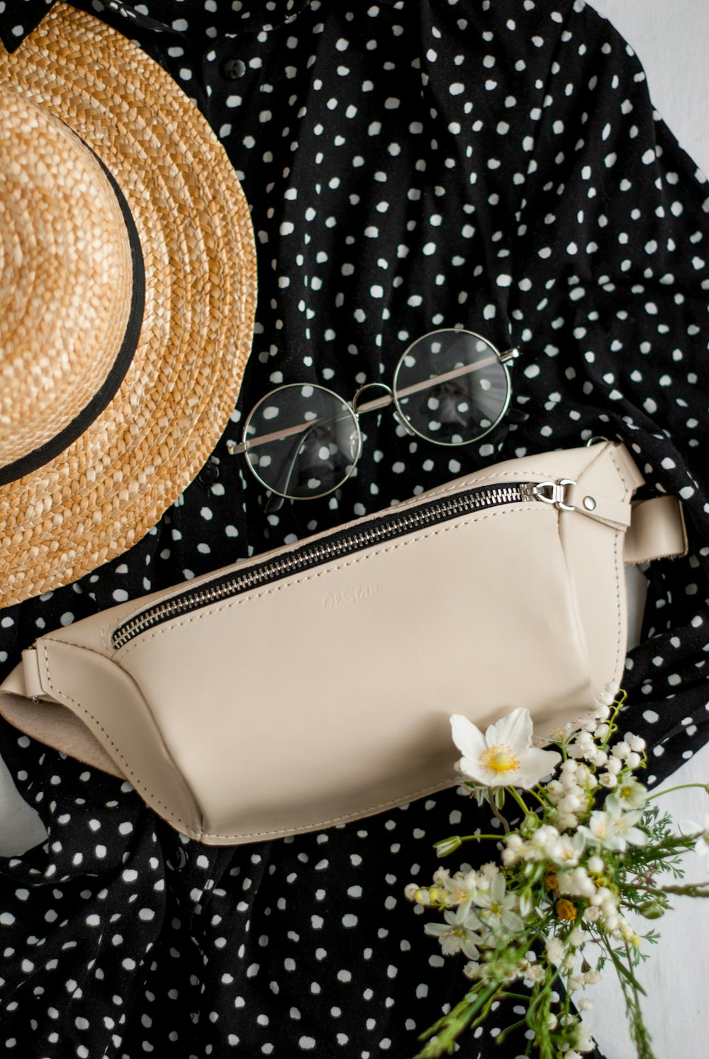 white leather sling bag beside brown straw hat