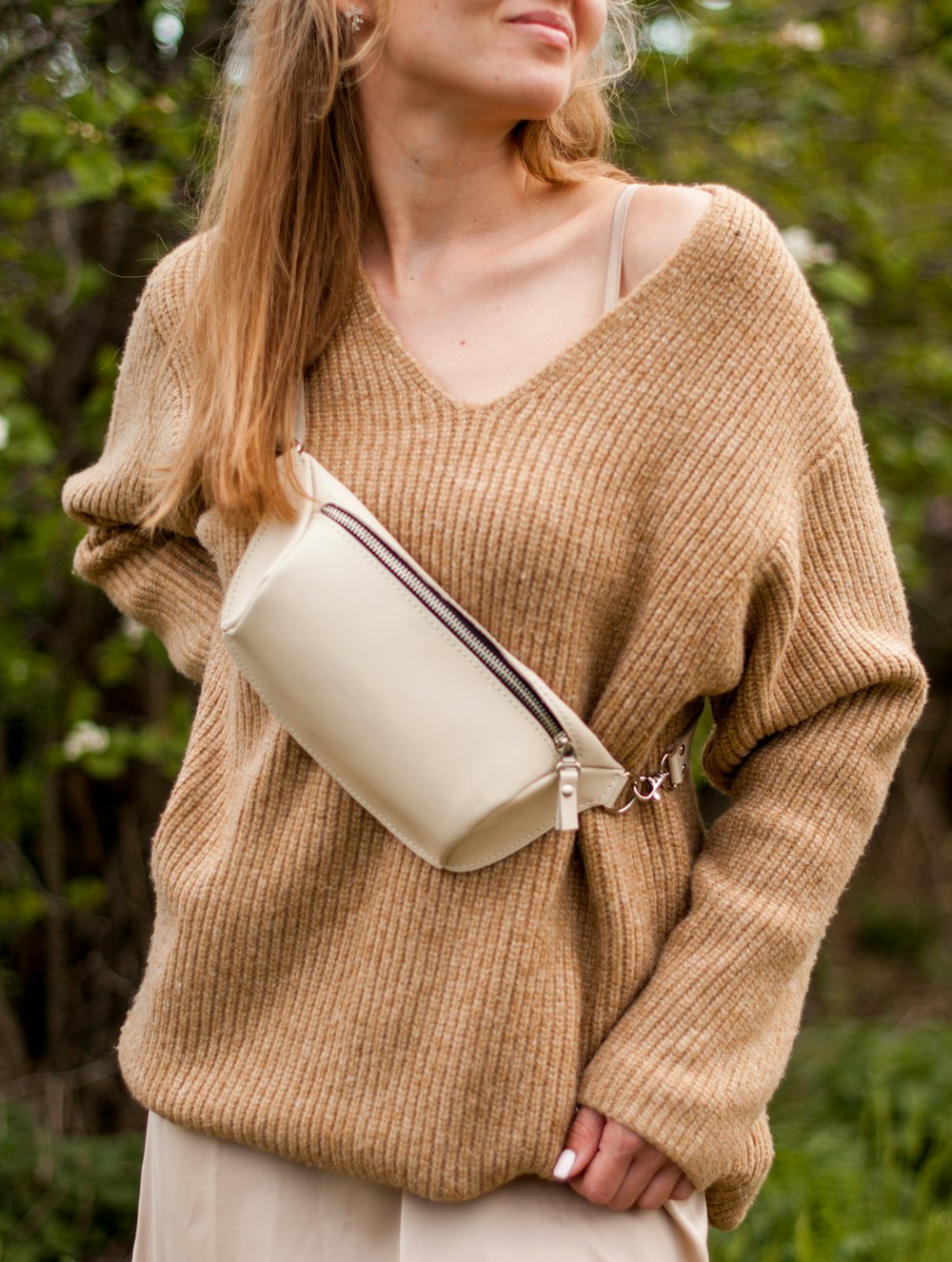 Mujer en suéter marrón sosteniendo una taza de cerámica blanca