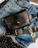 Un bolso negro encima de un par de jeans