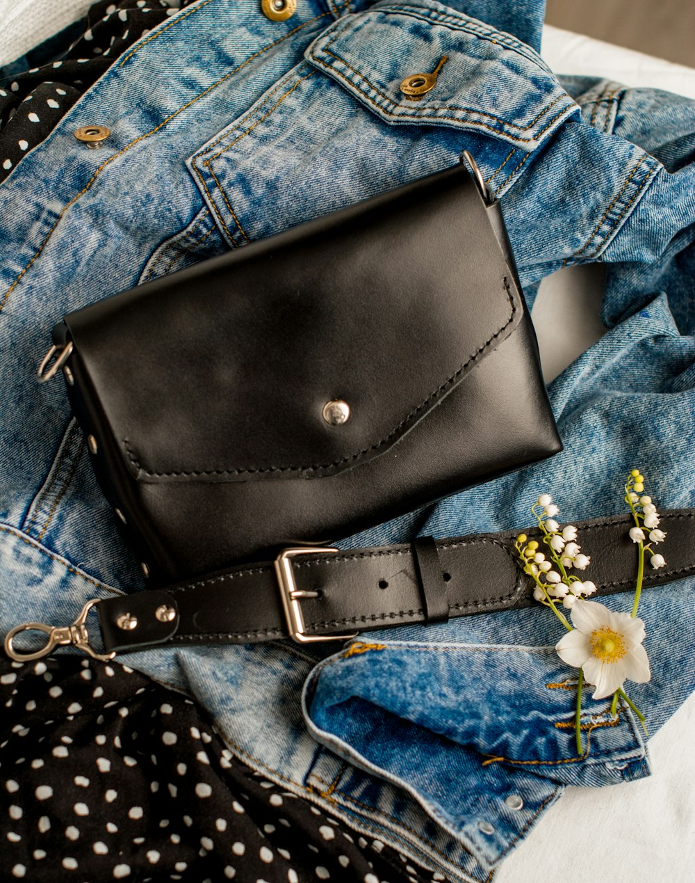 a black purse sitting on top of a pair of jeans