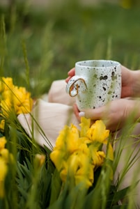 person holding white and black ceramic mug