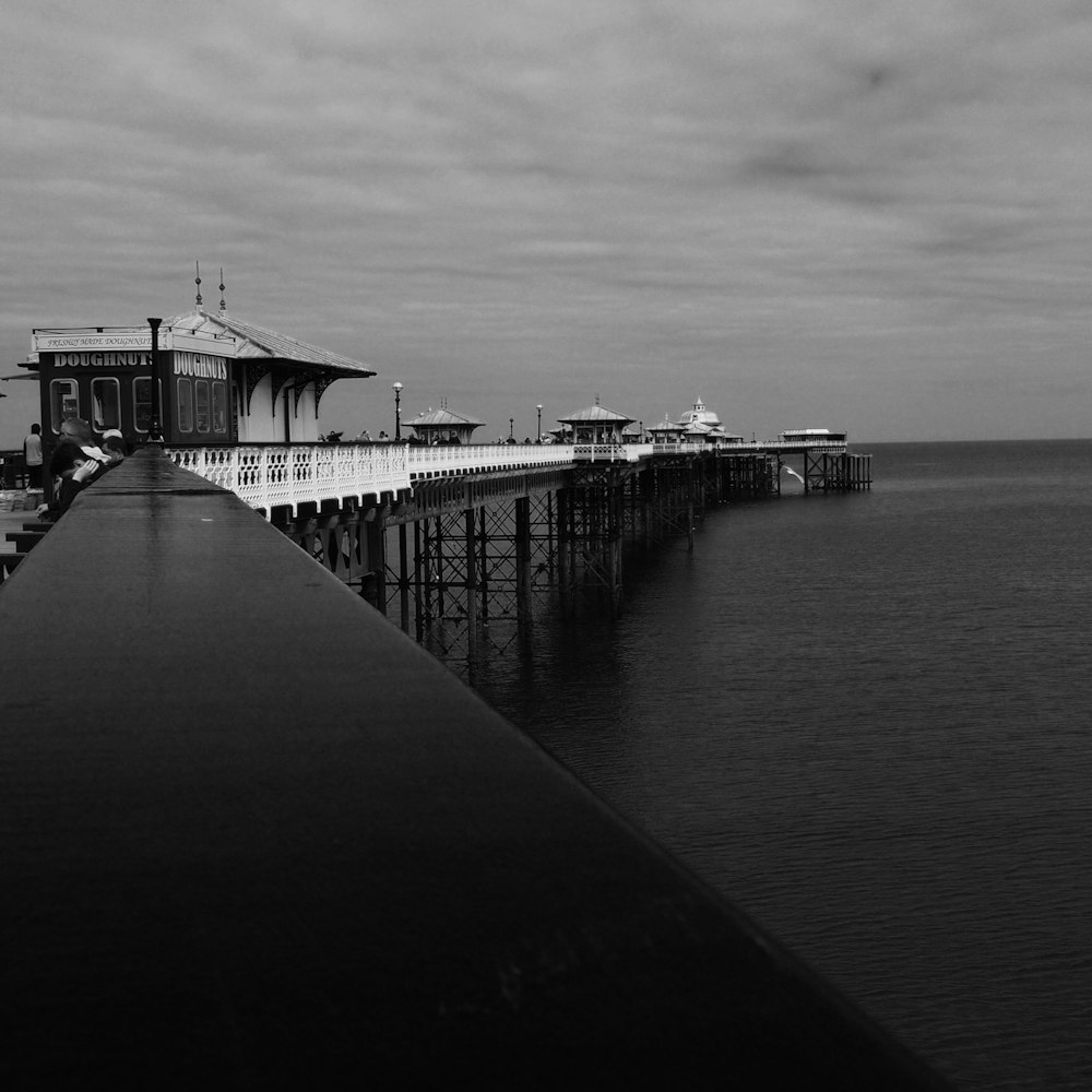 grayscale photo of dock on sea