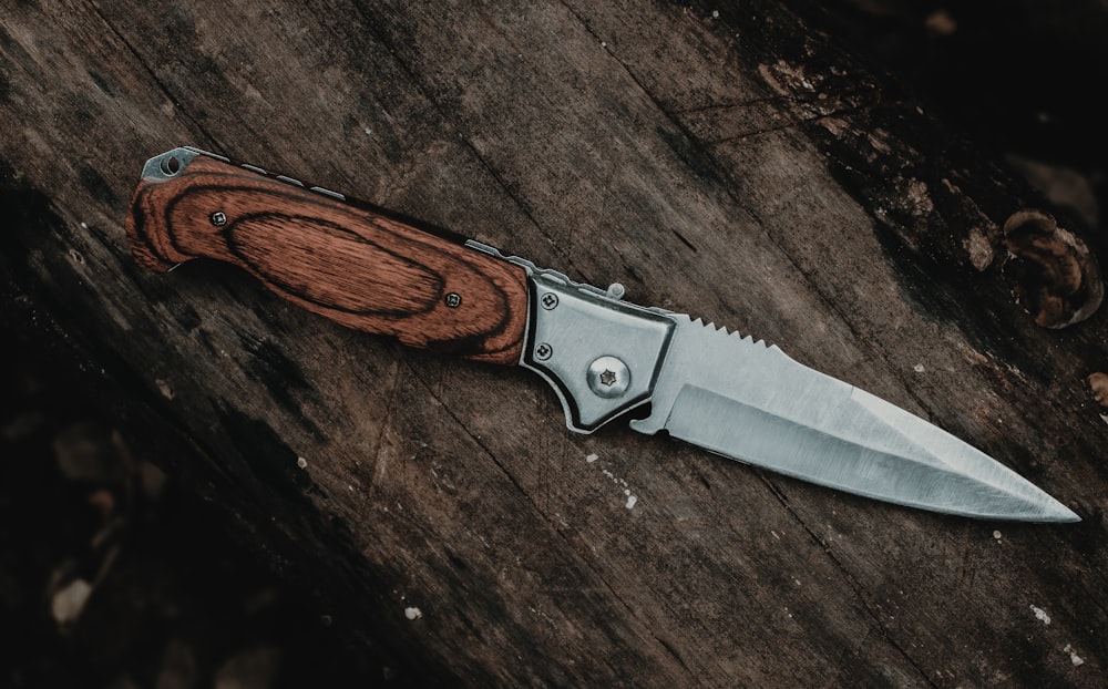 coltello d'argento con manico marrone su tavolo di legno marrone