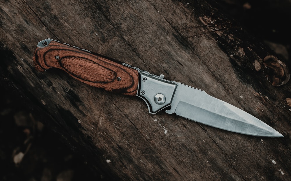 cuchillo plateado con mango marrón sobre mesa de madera marrón