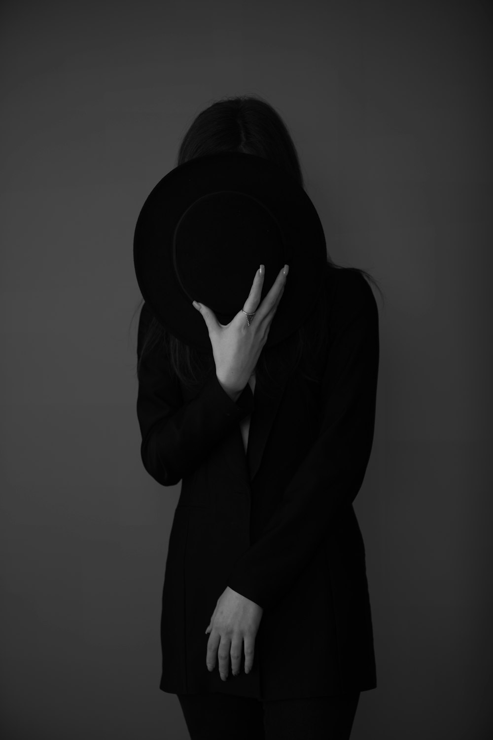 person in black hoodie covering face with hands