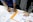 person in blue shirt writing on white paper