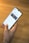 A hand is holding a smartphone displaying a website with the header 'LE SOLUZIONI'. The smartphone screen shows a section with an image of a person and text underneath. The background is a wooden table surface.