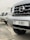 A close-up view of several parked Nissan cars, focusing on the front grille and license plate of the nearest vehicle, which has a Dubai registration number.