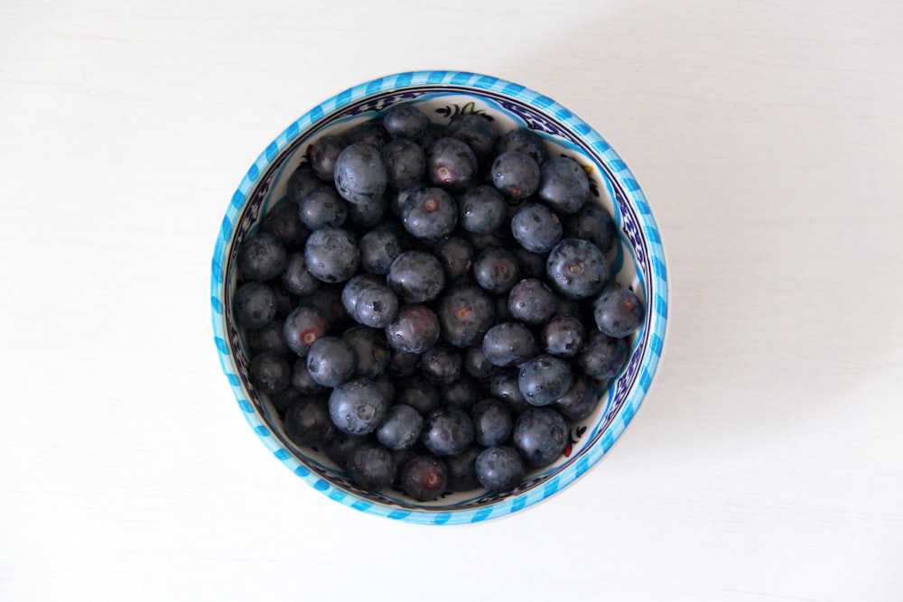 schwarze runde Früchte in blauer Keramikschale