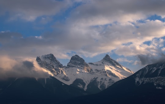 snow covered mountain under cloudy sky during daytime in The Three Sisters Canada