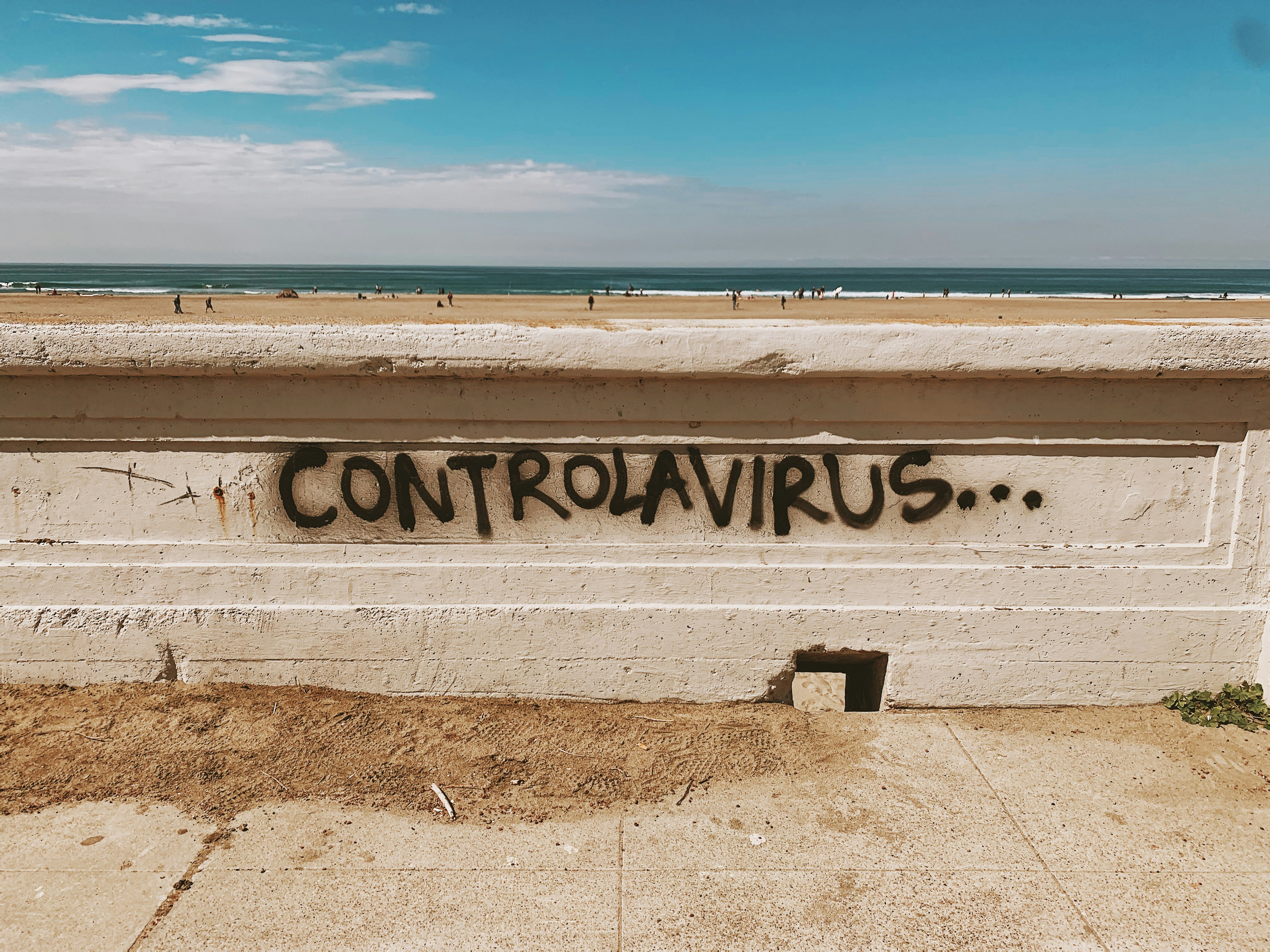 white wooden bench on brown sand near sea under blue sky during daytime