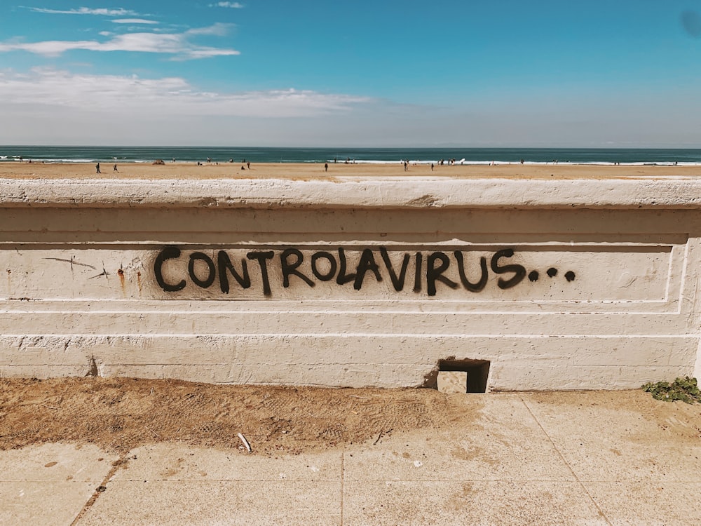 banco de madera blanca sobre arena marrón cerca del mar bajo el cielo azul durante el día