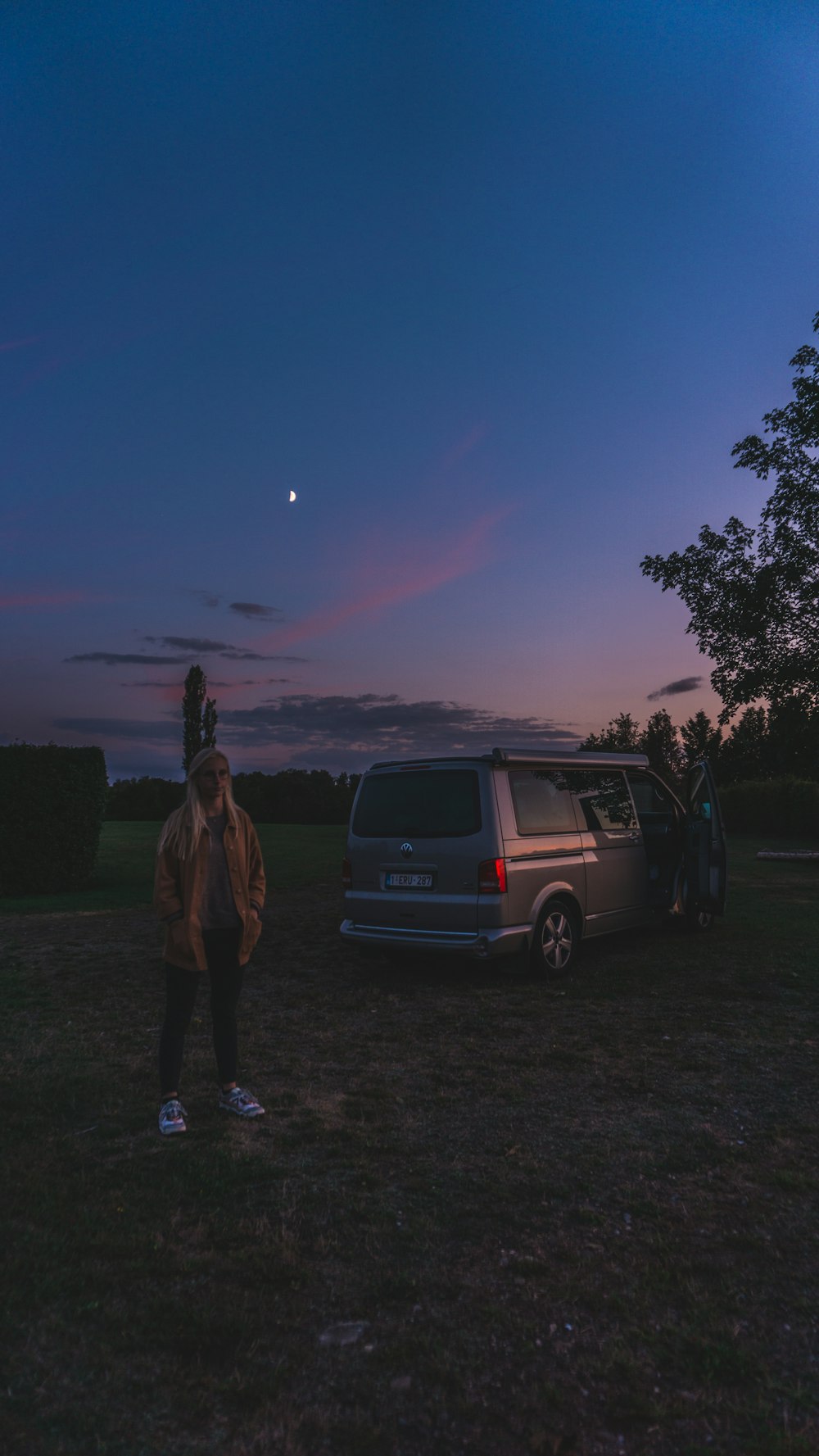 man in brown jacket standing beside black suv during night time