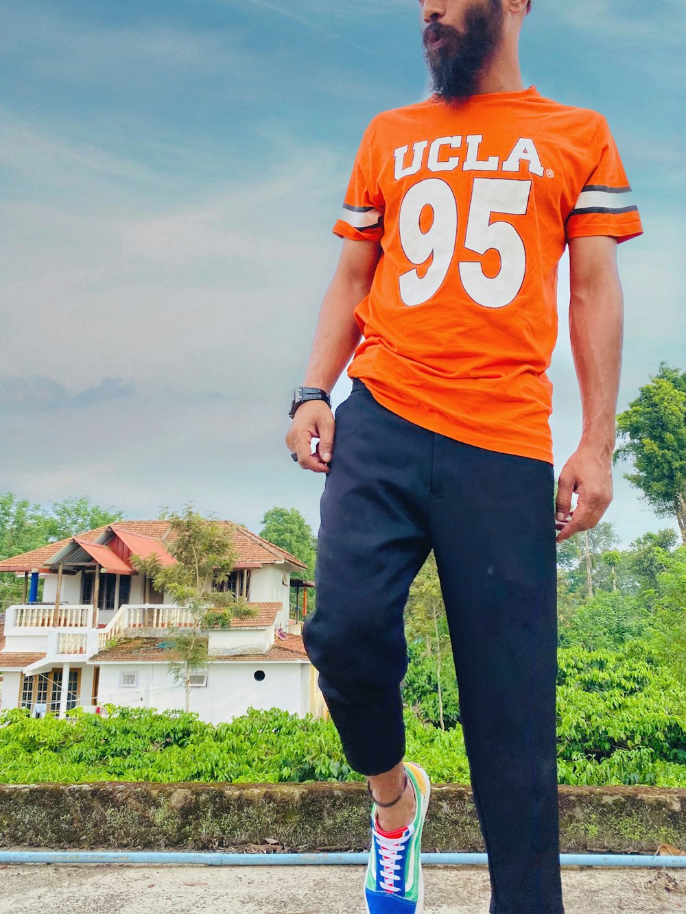 man in orange and white t-shirt and black pants standing on green grass field during