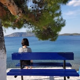 woman sitting on bench near body of water during daytime