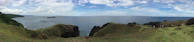 Tourists hiking along a scenic trail with panoramic views of the ocean and cliffs.