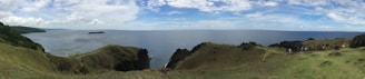 Hikers walking along a lush coastal trail with panoramic views of the sea.