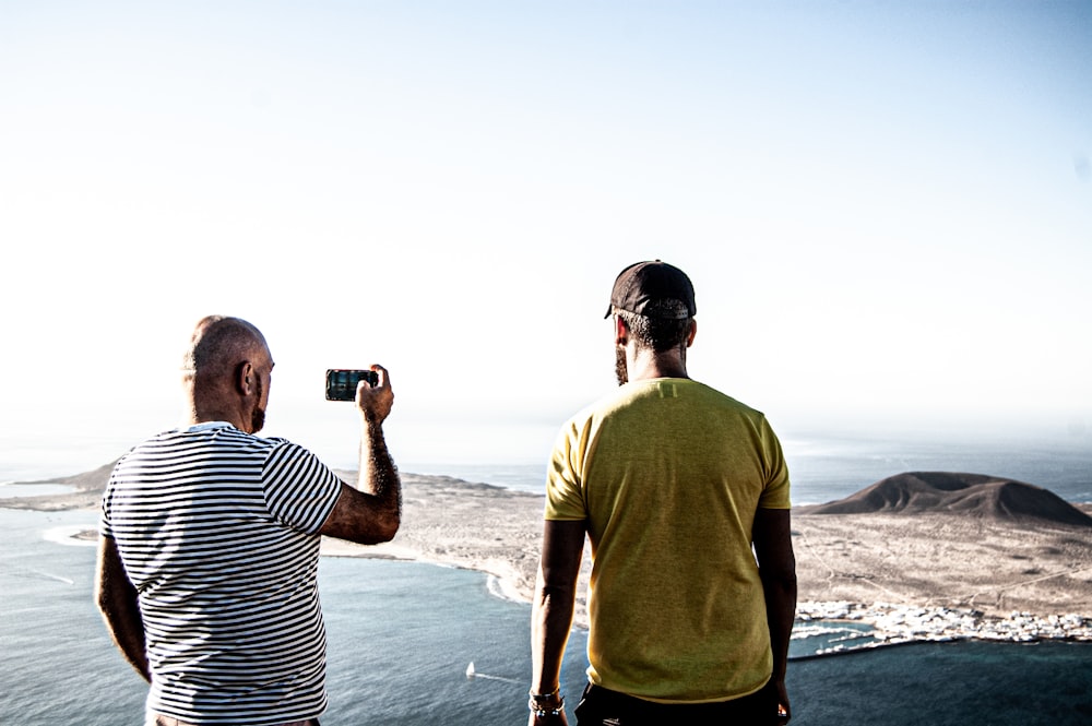 man in brown shirt holding black smartphone