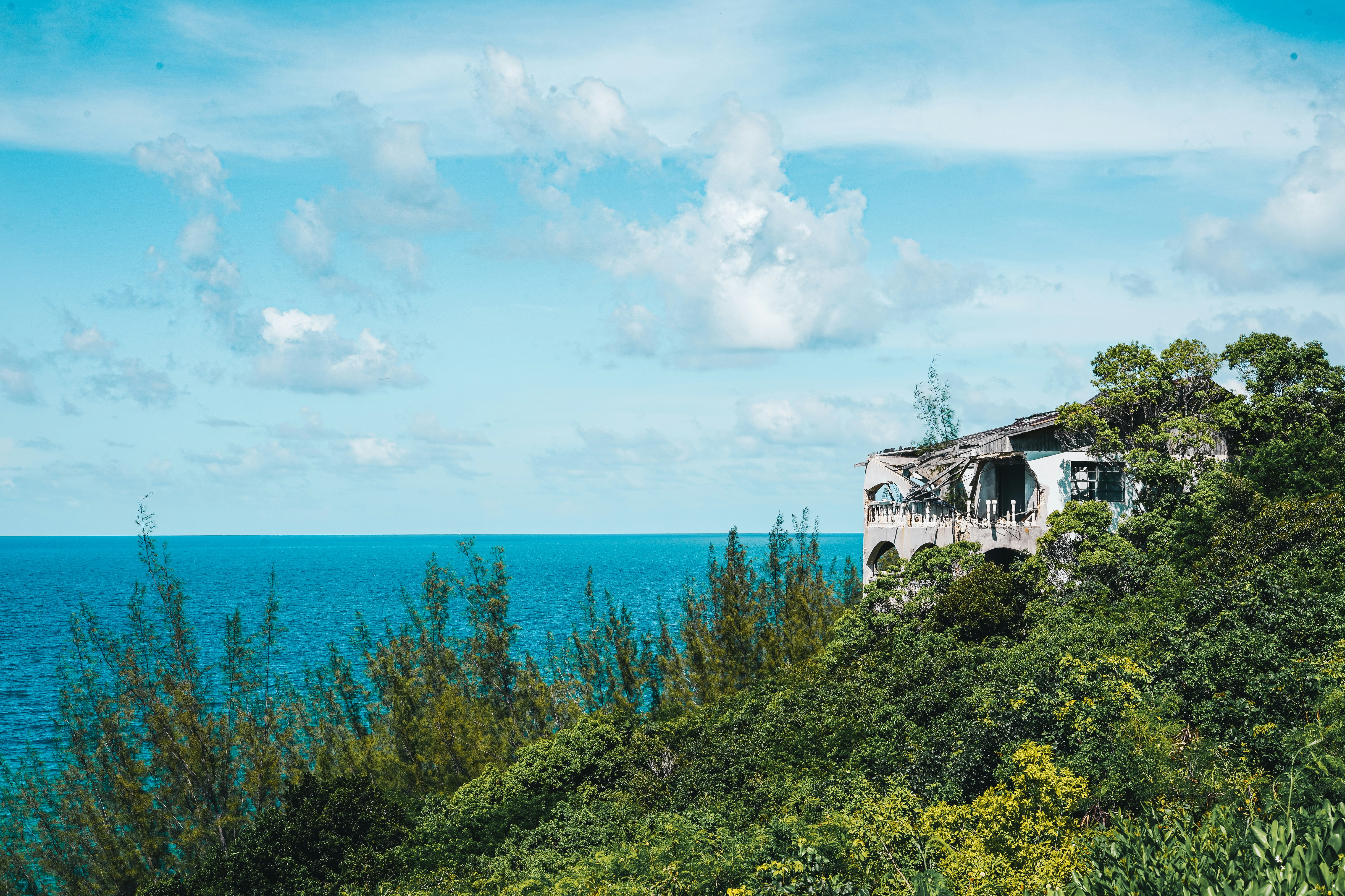 white and brown concrete building near green grass field under blue sky and white clouds during, An abandoned house that was hit by a hurricane on the beautiful island of Eleuthera in the Bahamas. 